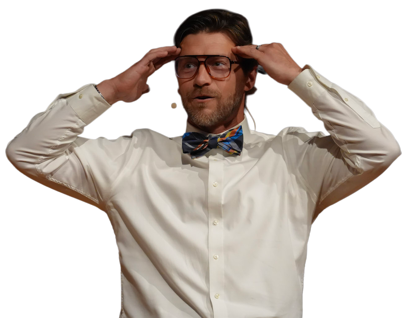 Ryan Koral on stage — mid-gesture, glasses, bow tie